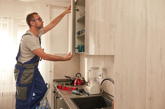 carpenter-installing-kitchen-cabinets A carpenter installing kitchen cabinets