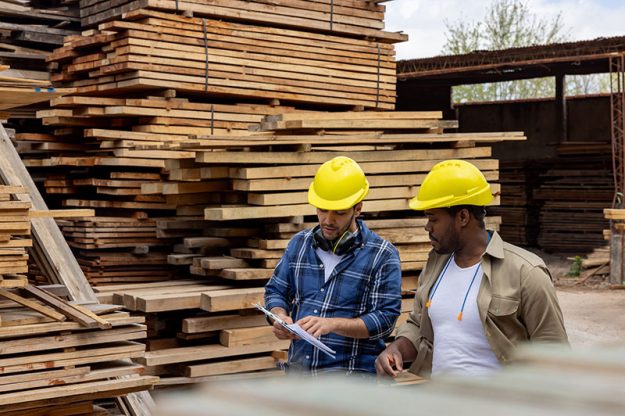 workers-talking-near-stacks-wood-boards-in-local-lumber-yard Workers talking near stacks wood boards in a local lumber yard