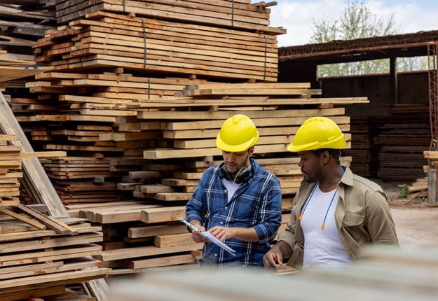workers-talking-near-stacks-wood-boards-in-local-lumber-yard Workers talking near stacks wood boards in a local lumber yard