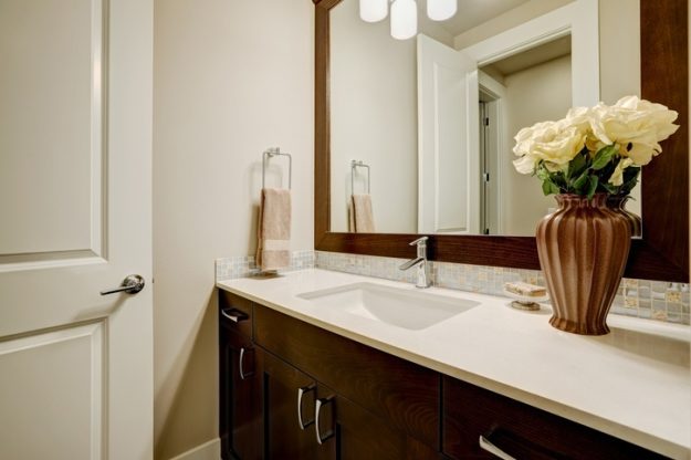 Modern bathroom vanity with dark wood cabinets, mosaic backsplash, and elegant decor