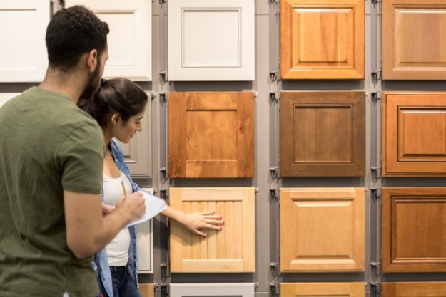 Couple examining cabinet door samples in a showroom, selecting styles and finishes