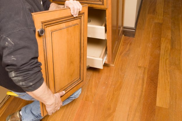 Close-up of a person handling a decorative wooden cabinet door during a refacing project, showcasing why cabinet refacing is a top choice for homeowners